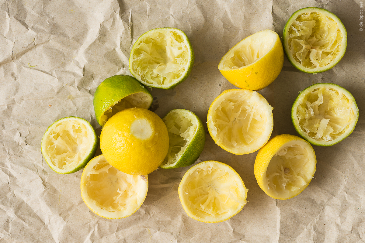 Zitronen und Limetten, halbierte und ausgepresste Früchte