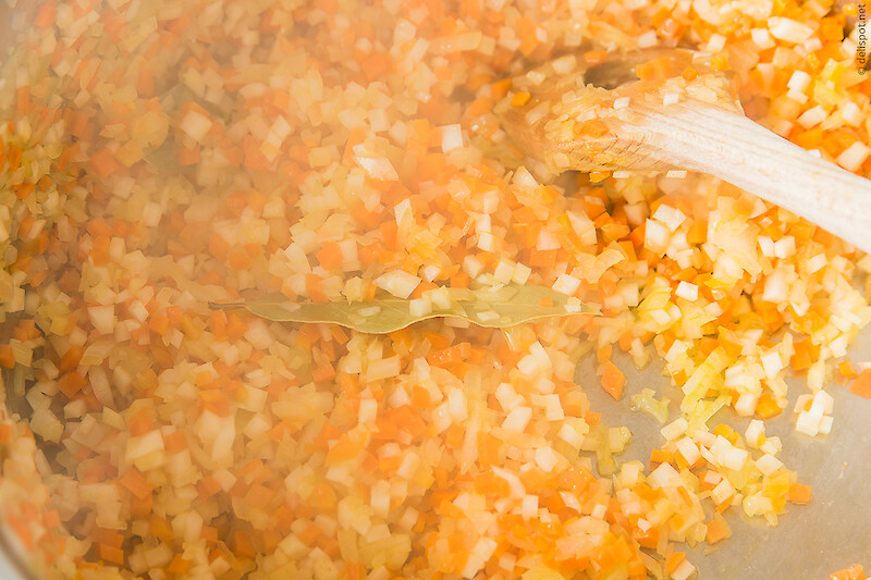 Kartoffelsuppe: feingewürfelte Zwiebeln, Karotten und Sellerie werden mit einem Lorbeerblatt angeschwitzt