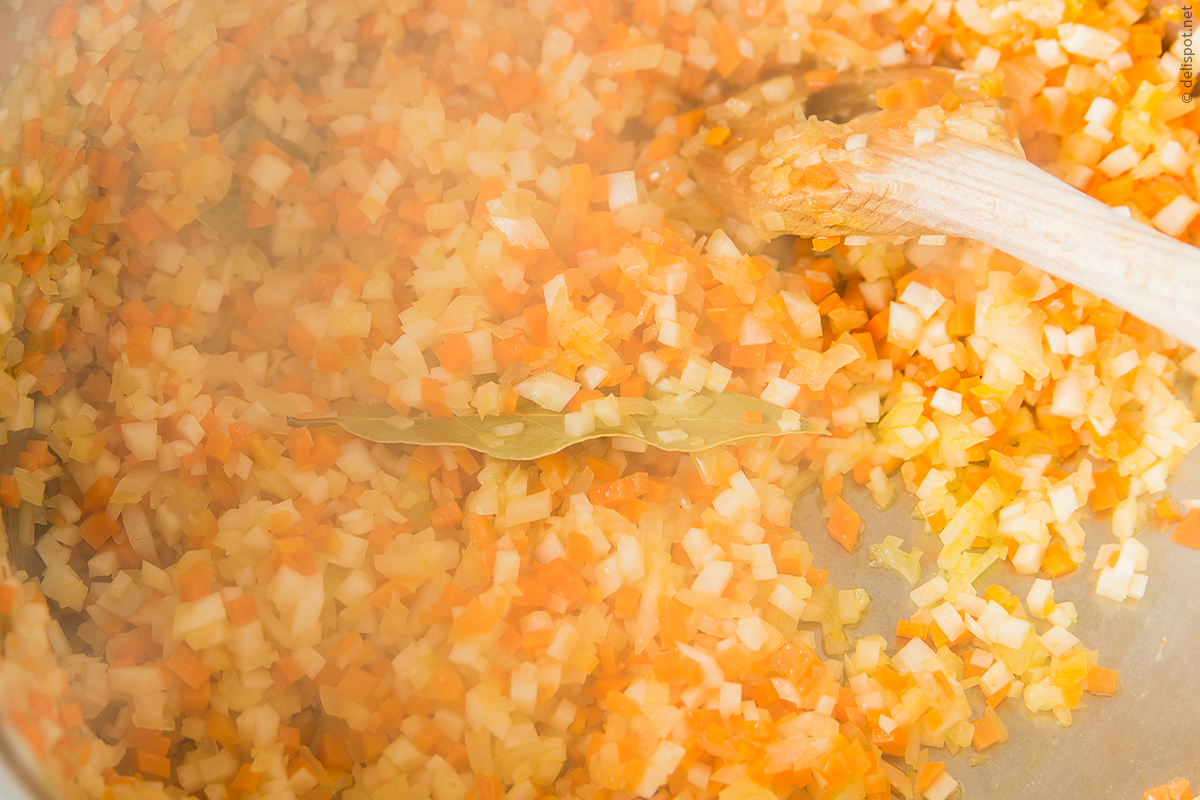 Kartoffelsuppe: feingewürfelte Zwiebeln, Karotten und Sellerie werden mit einem Lorbeerblatt angeschwitzt