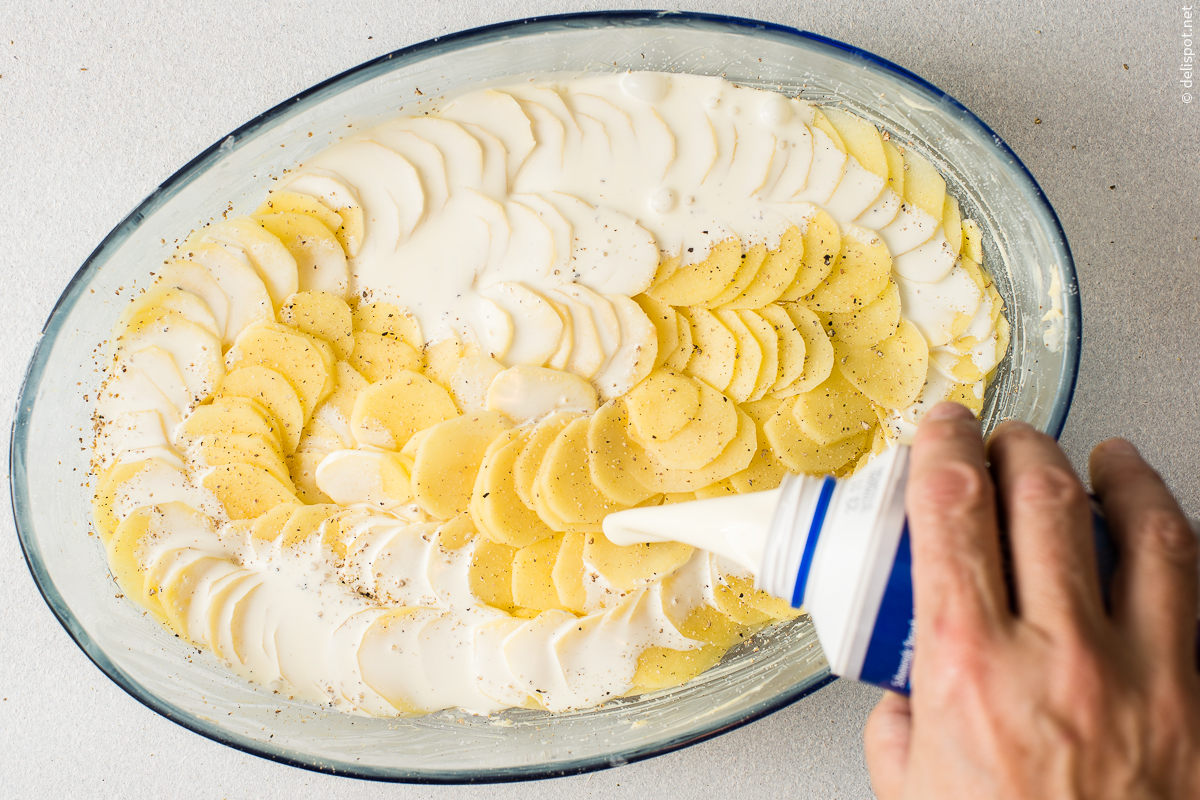 Zubereitung Kartoffelgratin, Kartoffelscheiben dachziegelartig schichten und mit Sahne begießen