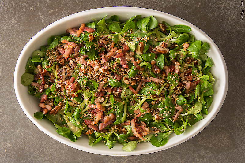 Feldsalat mit Sauce Vinaigrette, kross gebratenen Speckstreifen, Pekannüssen und Sesam