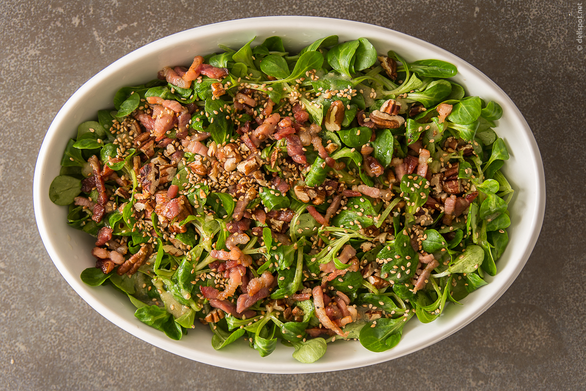 Feldsalat mit Sauce Vinaigrette, kross gebratenen Speckstreifen, Pekannüssen und Sesam