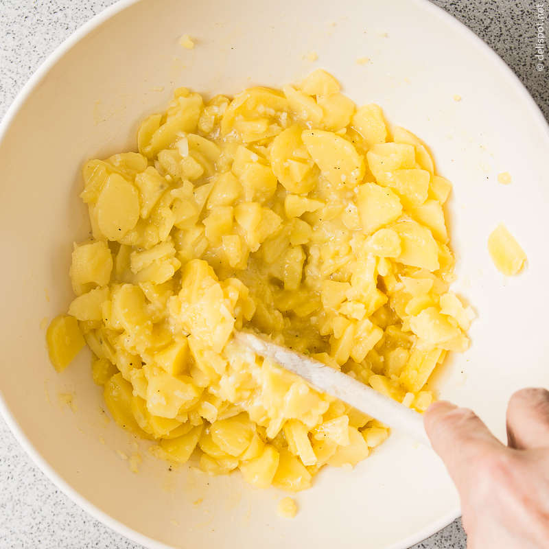Kartoffelsalat: Pellkartoffeln mit dem Dressng verrühren und einige Stunden ziehen lassen