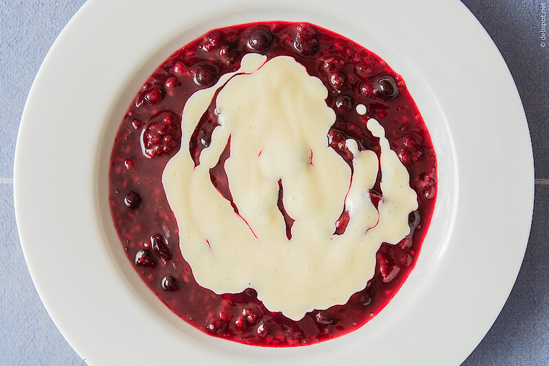 Vanillesauce als Topping auf roter Grütze