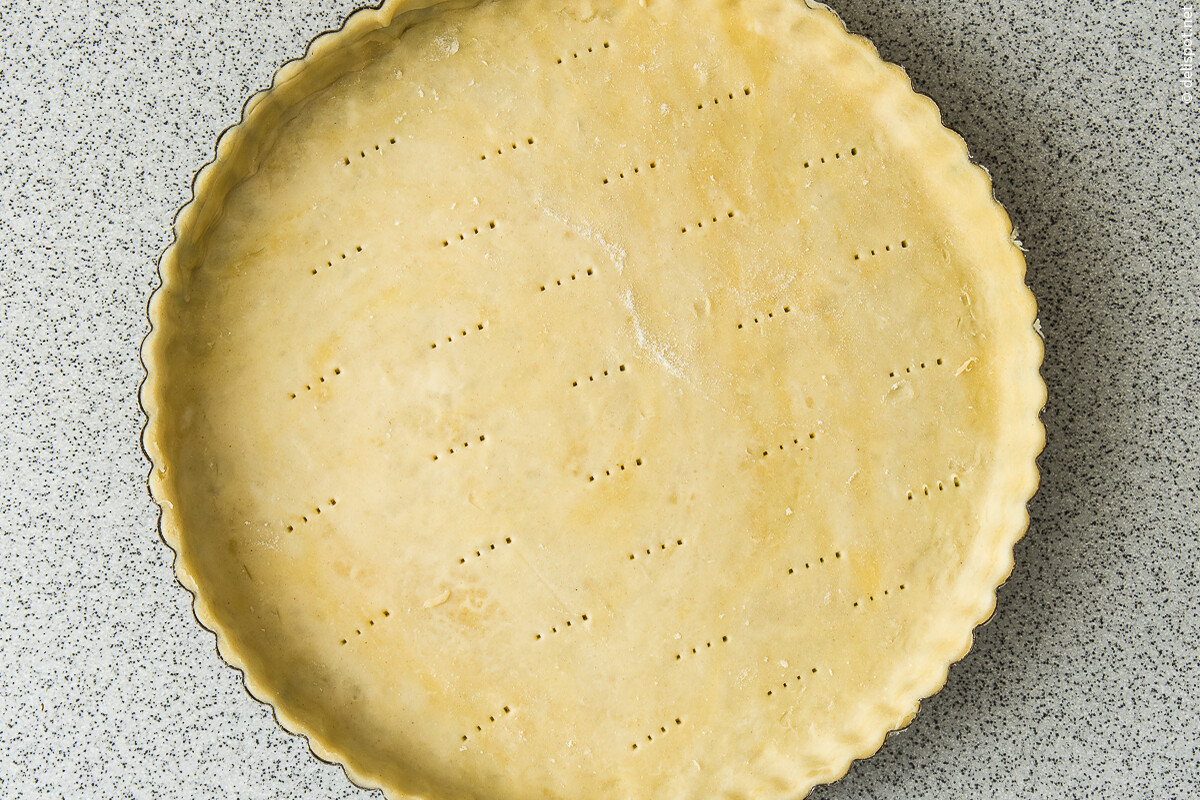 Mürbeteig, ausgerollt, in Tarteform ausgelegt und perforiert