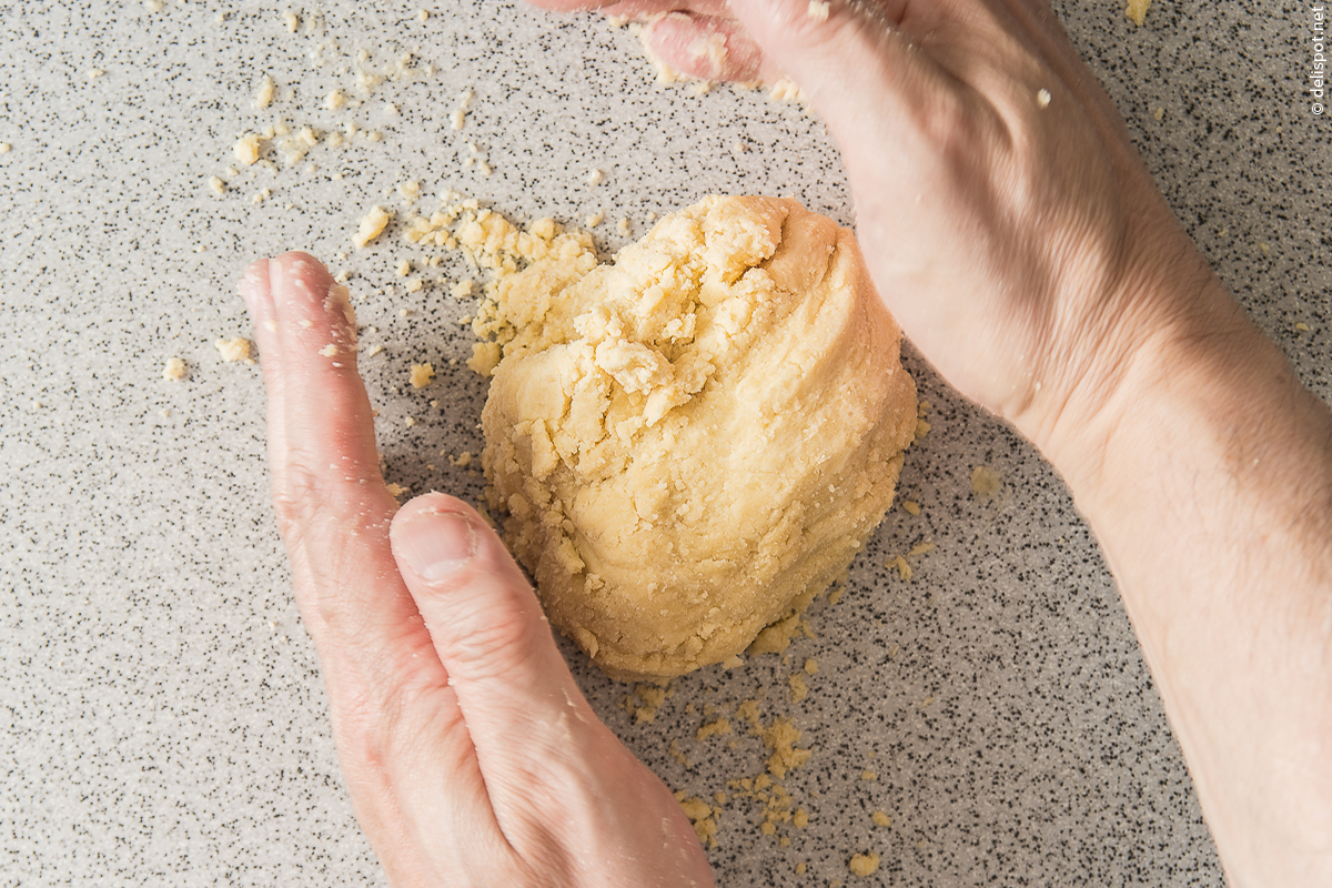Mürbeteig, Herstellung: Wasser zügig in die Mehl-Butter-Mischung einarbeiten, ohne den Teig zu kneten