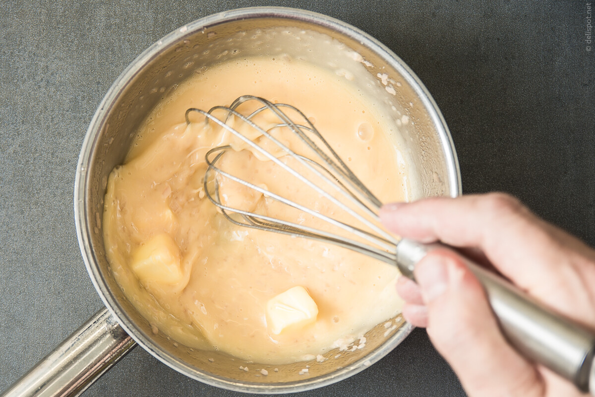 Herstellung von Beurre blanc: Kalte Butterwürfel werden mit Schneebesen einmontiert