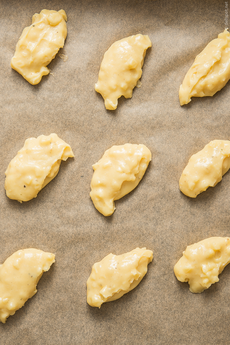 Gougères im Rohzustand: mit Käse vermischter Brandteig, mit zwei Löffeln zu Nocken geformt