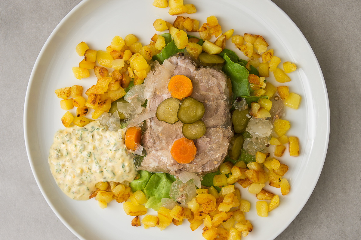 Sauerfleisch, angerichtet mit Karotten, Essiggurken, Bratkartoffeln und Remoulade