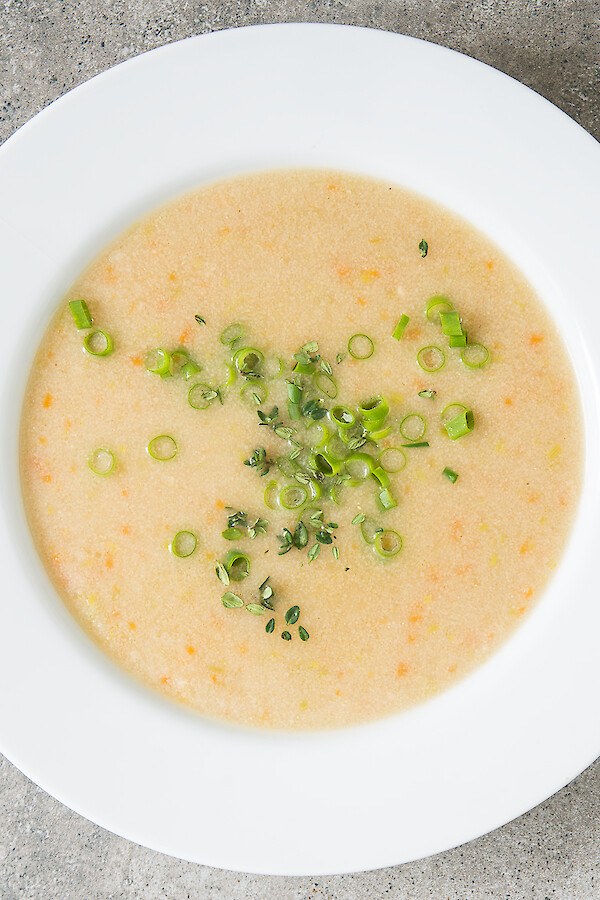 Gebrannte Grießsuppe, in Teller angerichtet, mit kleingeschnittenen Lauchzwiebeln und Thymianblättchen bestreut