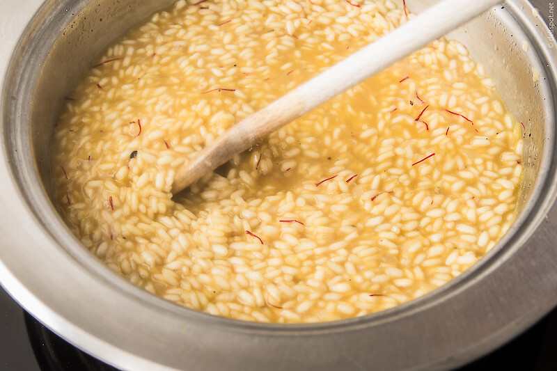 Risotto-Zubereitung: Zugabe von eingeweichten Safranfäden nach etwa der halben Garzeit