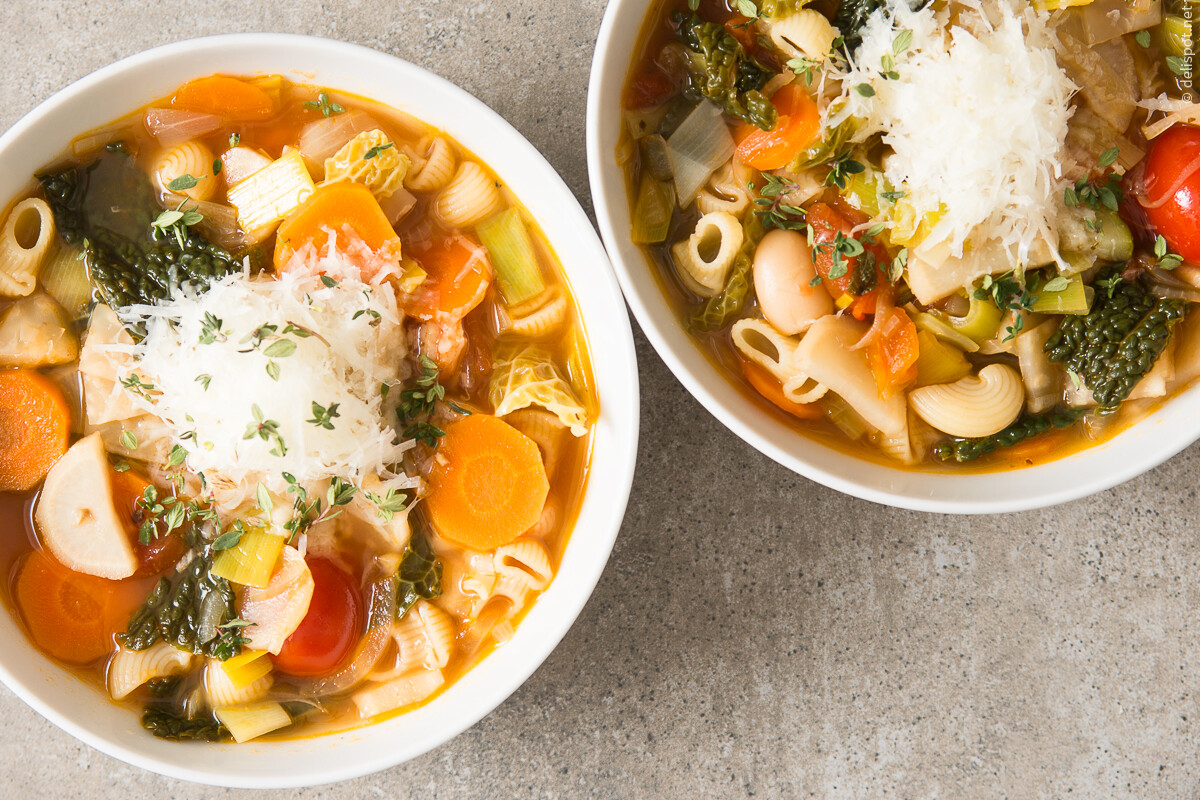 Minestrone, Gemüsesuppe, angerichtet in zwei Schalen, mit Käse und Thymian bestreut