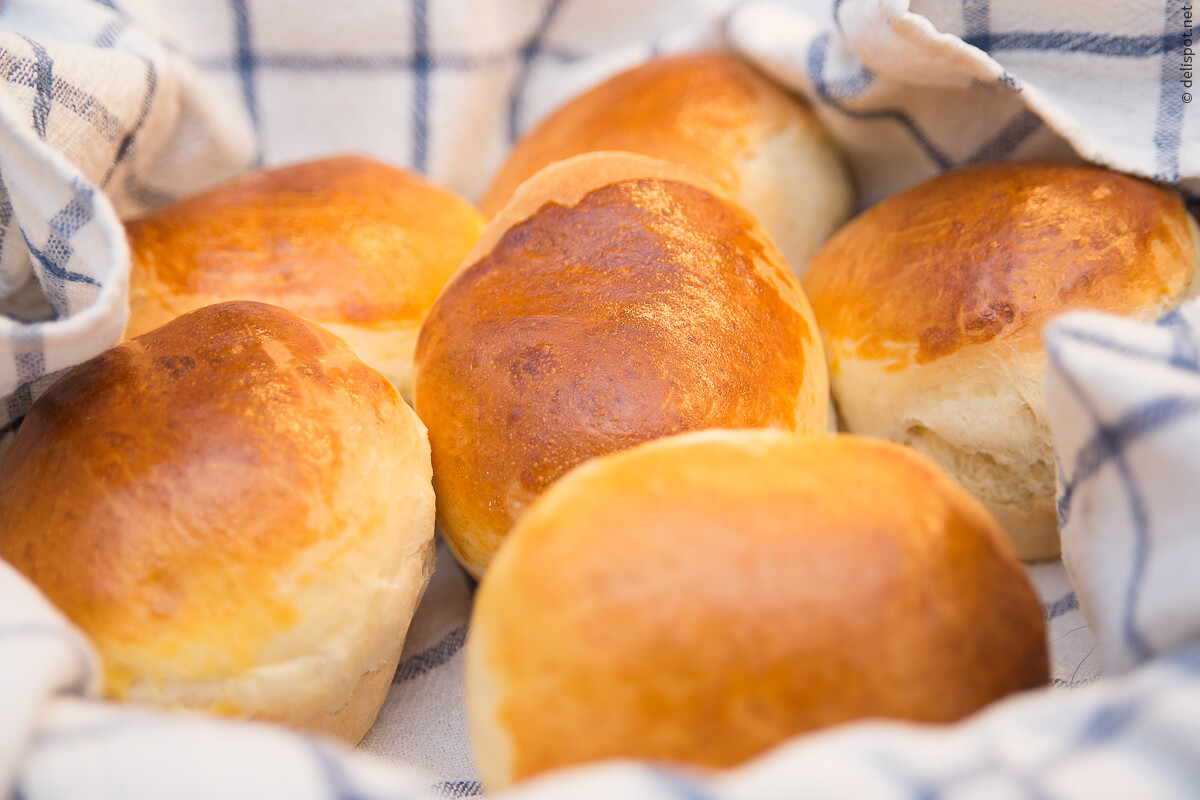 Brioche, runde Einzelstücke, frisch gebacken im Brotkorb, eingeschlagen in ein Tuch