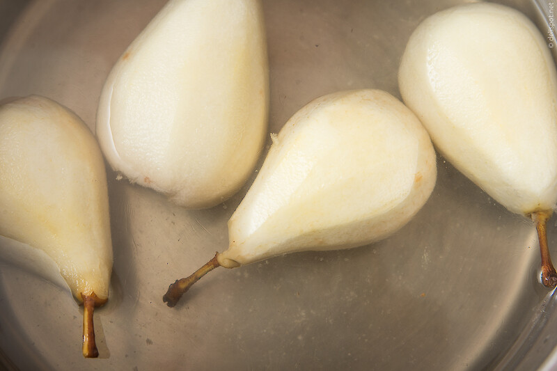 Vier geschälte und entkernte kleine Birnen pochieren in Vanillesirup