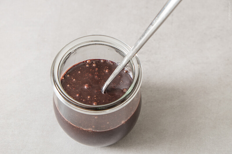 Chocolate Fudge Sauce, abgefüllt in Glas, in dem ein langer Löffel steckt
