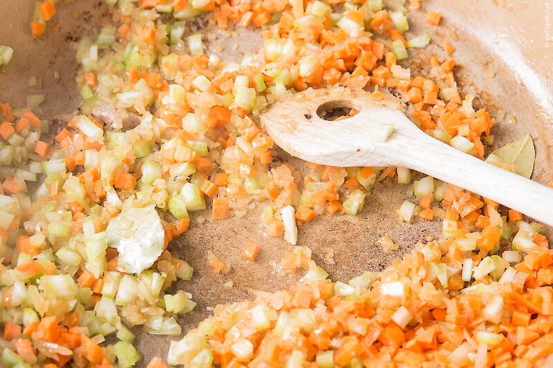 Zur Herstellung eines Soffritos werden feine Würfel von Zwiebeln, Karotten und Staudensellerie zusammen mit Lorbeerblättern angeschwitzt