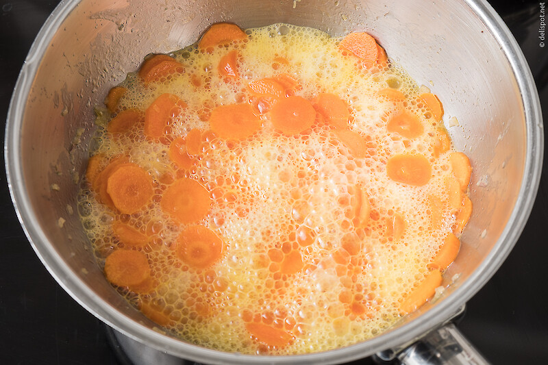 Angeschwitze Karotten werden mit kohlensäurehaltigem Mineralwasser abgelöscht, was eine starke Bläschenbildung auslöst