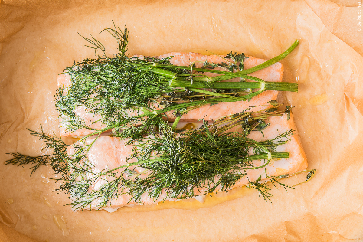Lachs en papillote: Lachs in Backpapier, in dem er im Backofen gedünstet wurde, zum Aromatisieren mit Dillzweigen belegt