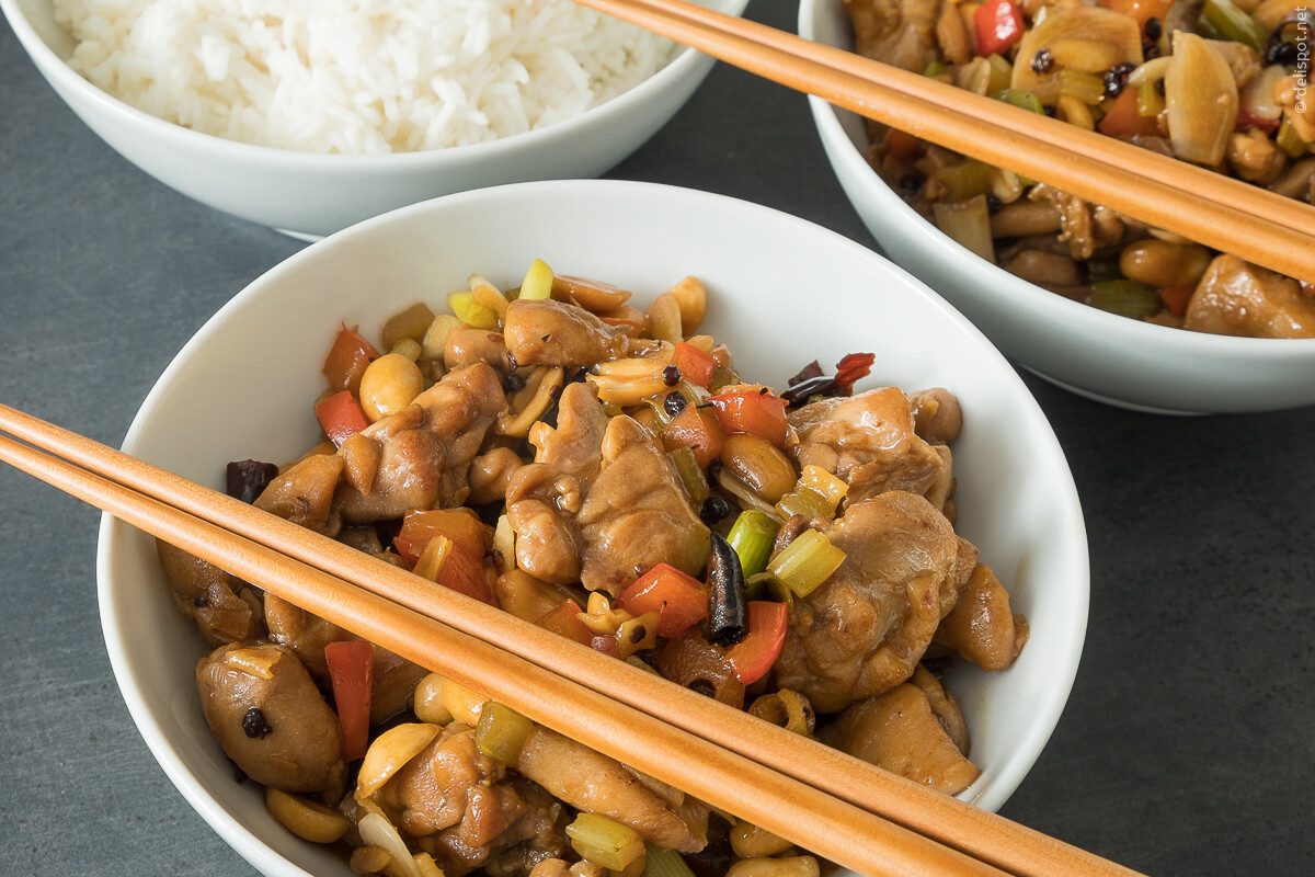 Gong Bao Ji Ding (Gong Bao Huhn) ein Gericht der chinesischen Küche, angerichtet in zwei Schalen, im Hintergrund eine Schale Reis