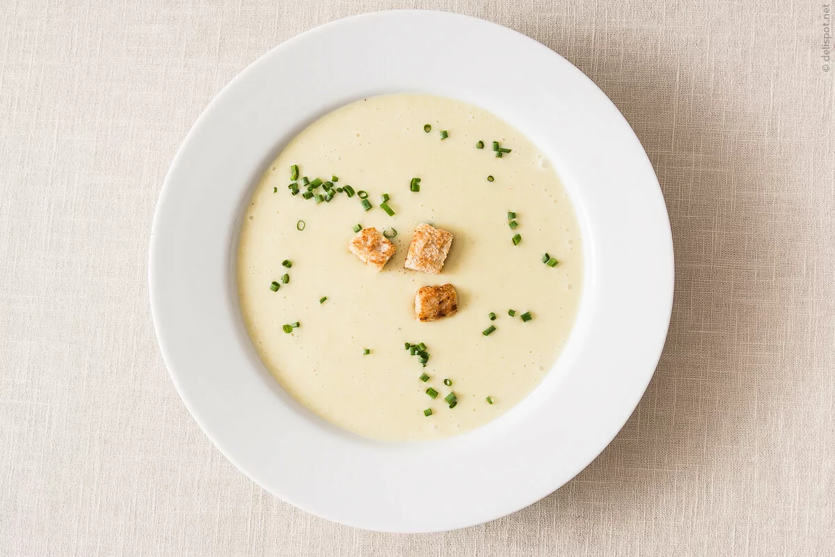 Vichyssoise, kalte Suppe aus Lauch und Kartoffeln, angerichtet in Suppenteller, bestreut mit Schnittlauch und Croûtons
